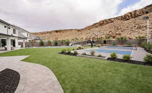 Fenced backyard with a patio area, basketball hoop, and a mountain view