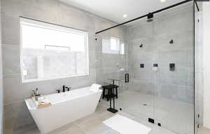 Bathroom featuring tile walls, a freestanding bath, a stall shower, tile patterned flooring, and recessed lighting