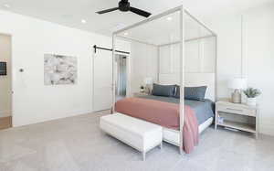 Carpeted bedroom with a barn door, ceiling fan, and recessed lighting