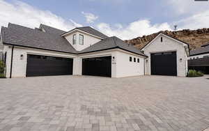 View of front of property featuring stucco siding, decorative driveway, stone siding, and an attached garage
