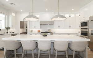 Kitchen with white cabinetry, a center island, a kitchen bar, and built in appliances