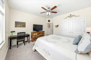 Bedroom featuring light carpet, ceiling fan, and a closet