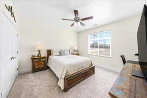 Bedroom featuring light colored carpet, ceiling fan, and a closet