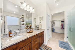 Bathroom featuring a spacious closet, double vanity, a stall shower, and recessed lighting