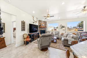 Living room featuring a ceiling fan, a stone fireplace, and recessed lighting