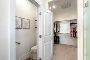 Bathroom with a walk in closet and light carpet