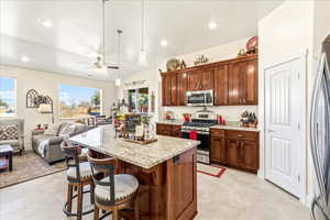 Kitchen featuring a breakfast bar, stainless steel appliances, open floor plan, light stone counters, and ceiling fan