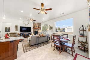 Living room with ceiling fan, a stone fireplace, and recessed lighting
