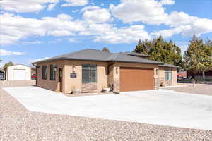 View of front of house with driveway, stone siding, stucco siding, and a metal roof