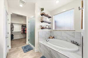 Full bath with a spacious closet, a stall shower, a bath, and recessed lighting
