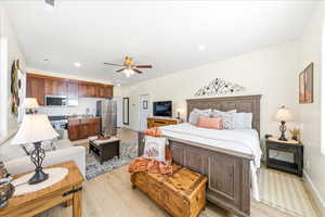 Bedroom with light wood finished floors, freestanding refrigerator, and recessed lighting