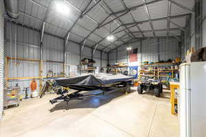 Garage with freestanding refrigerator, metal wall, and a workshop area