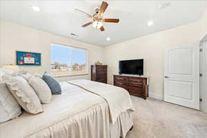 Bedroom featuring light colored carpet, ceiling fan, and recessed lighting