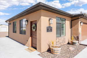 Property entrance featuring stucco siding, an attached garage, and stone siding