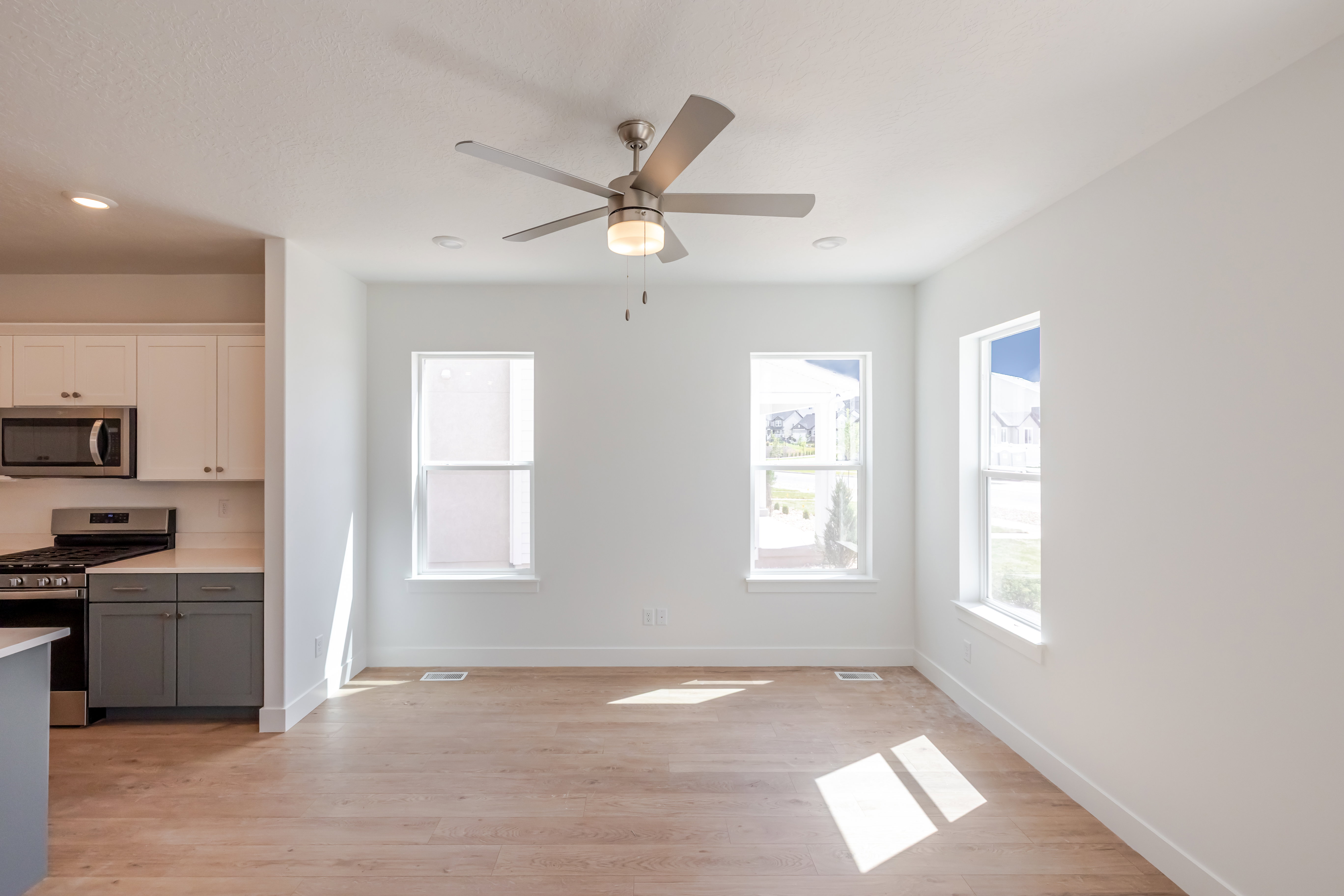 Bright open-concept living area featuring wood-finish flooring, recessed lighting, and a modern ceiling fan