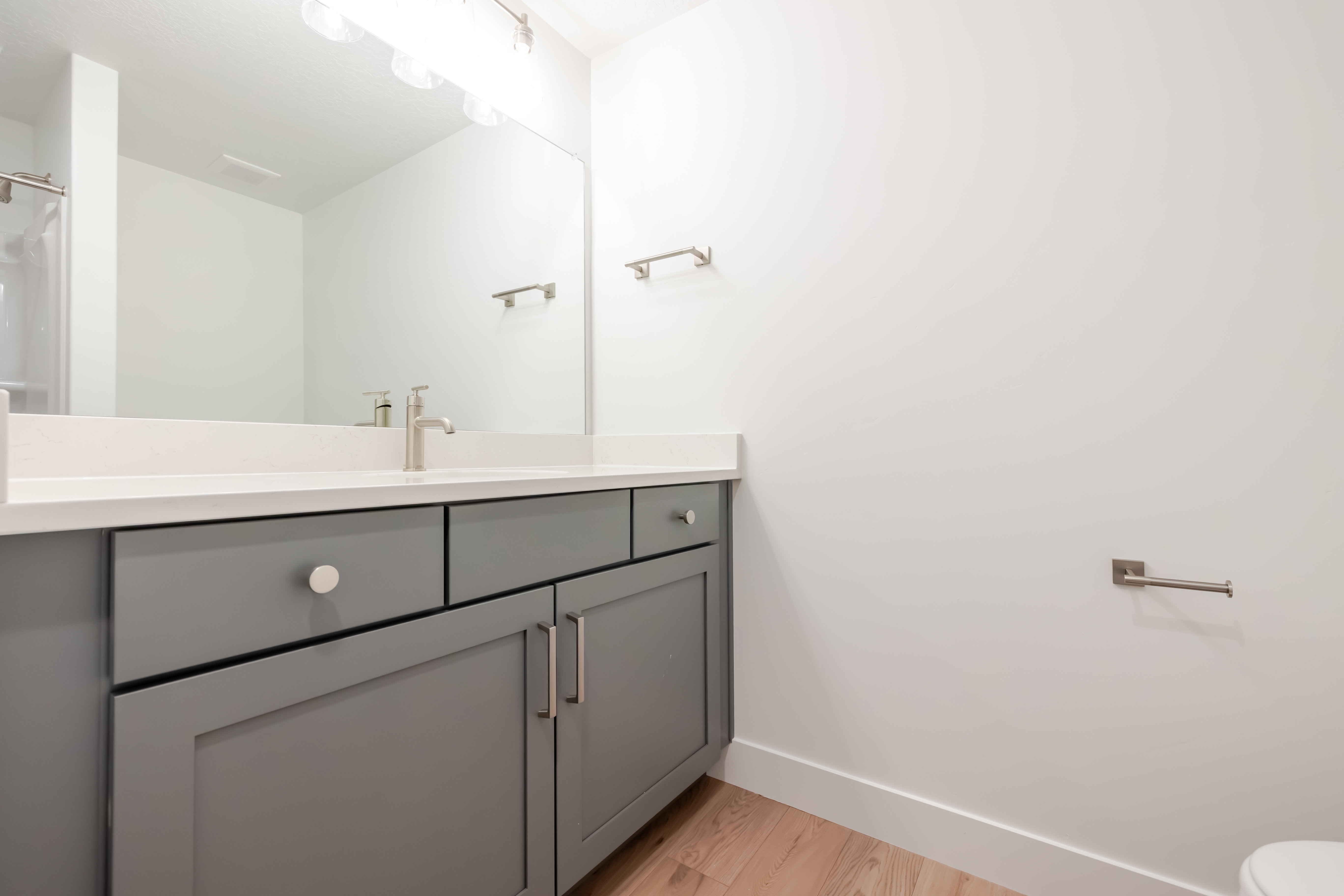 Contemporary bathroom vanity featuring gray cabinetry, a white countertop, and a brushed nickel faucet
