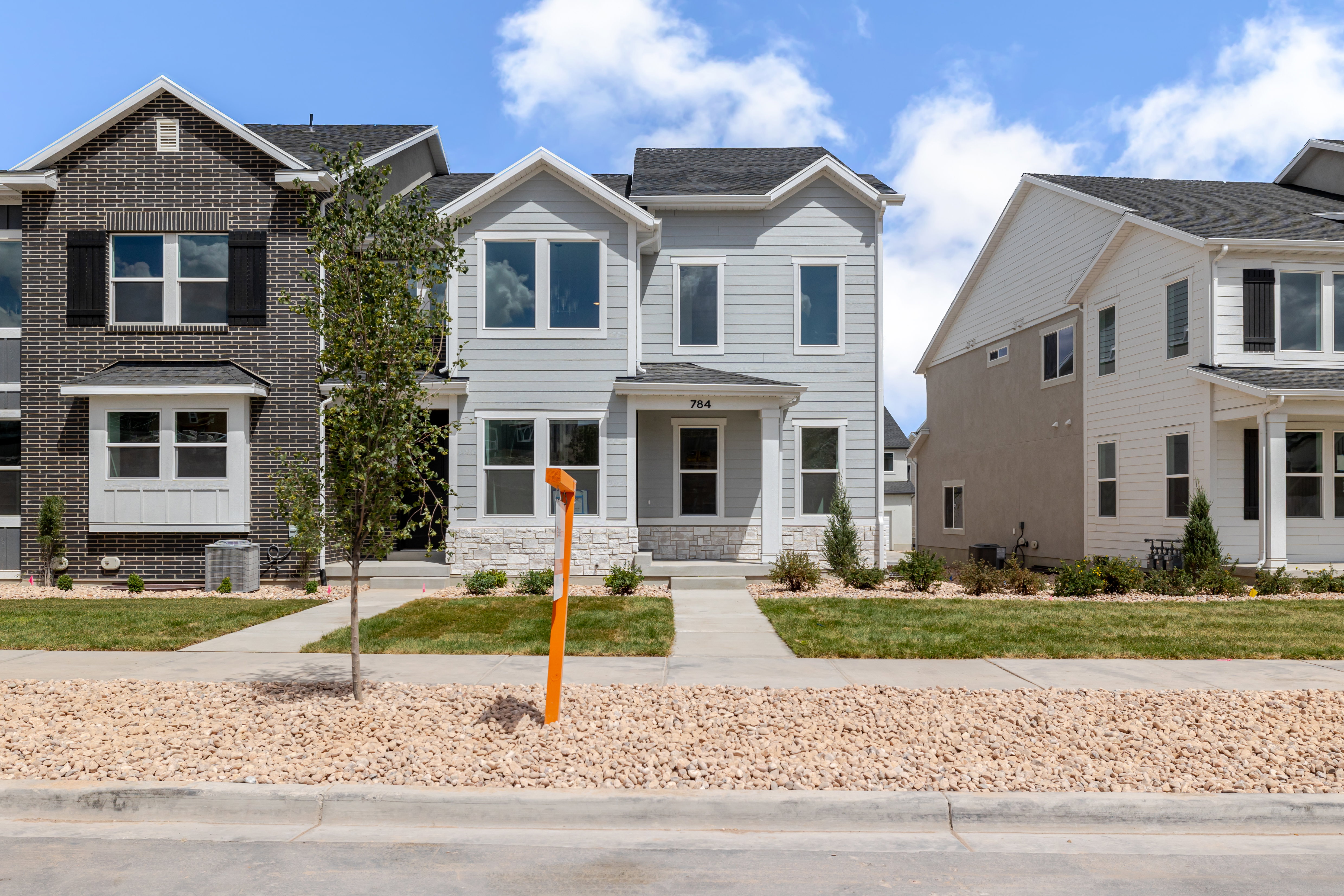 Contemporary two-story residence featuring light gray siding and white stone veneer accents