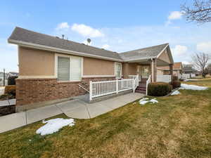View of front of home featuring brick siding, a front yard, stucco siding, and a shingled roof