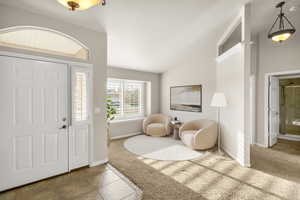 Carpeted foyer entrance featuring lofted ceiling and baseboards