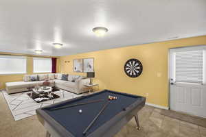 Rec room featuring pool table, a textured ceiling, and light colored carpet