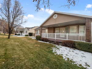 View of front of house featuring a porch, stucco siding, a front yard, and brick siding