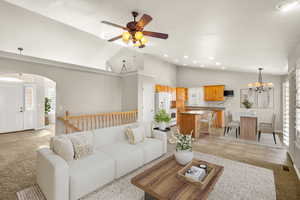 Living room with hanging lights, lofted ceiling, arched walkways, ceiling fan, and light tile patterned floors