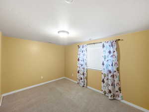 Unfurnished room with light carpet and a textured ceiling