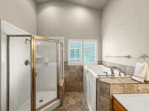 Bathroom featuring a shower stall, a bath, tile walls, a high ceiling, and vanity