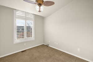 Unfurnished room featuring dark carpet, a ceiling fan, and lofted ceiling