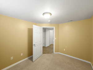 Unfurnished bedroom featuring light carpet and baseboards
