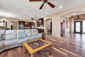 Living room featuring arched walkways, hanging lights, a ceiling fan, and light wood finished floors