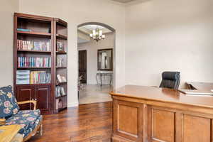 Office space with dark wood-style flooring, arched walkways, and suspended lighting
