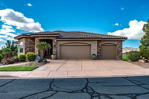 View of front of property featuring stone siding, a tiled roof, stucco siding, driveway, and a garage