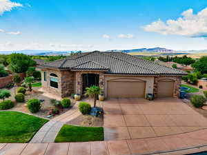 View of front of property featuring stone siding, an attached garage, stucco siding, and a tiled roof