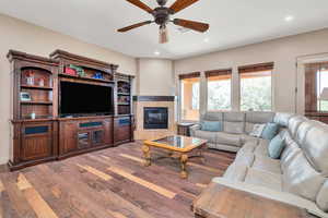 Living area featuring wood finished floors, ceiling fan, a tiled fireplace, and recessed lighting