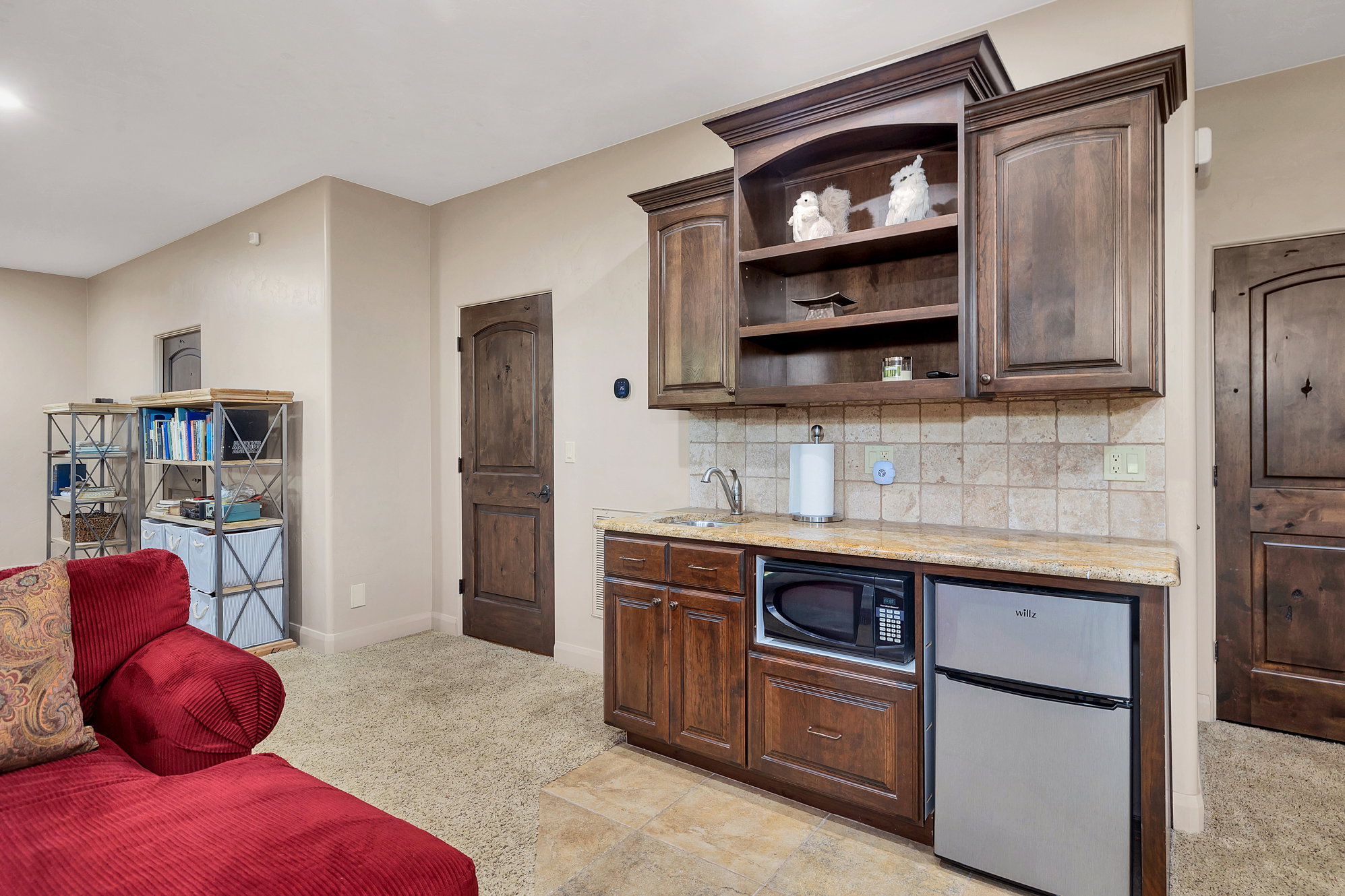 Kitchen with freestanding refrigerator, open shelves, dark wood finish cabinetry, and backsplash