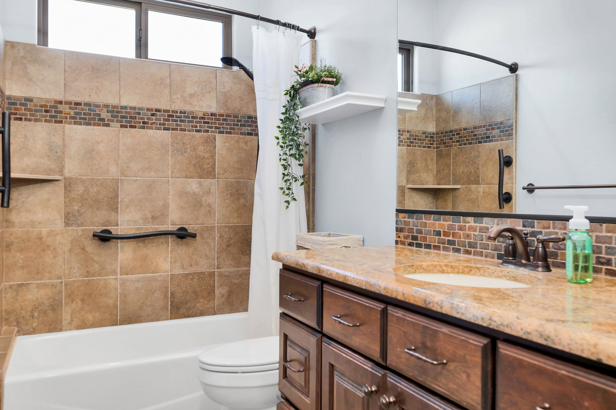 Bathroom featuring vanity, shower / bath combo, and tasteful backsplash