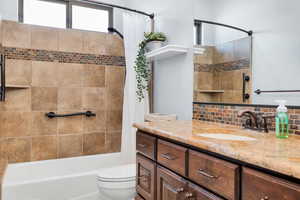 Bathroom featuring vanity, shower / bath combo, and tasteful backsplash
