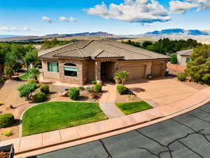 Mediterranean / spanish home featuring stone siding, driveway, a tile roof, a garage, and a mountain view