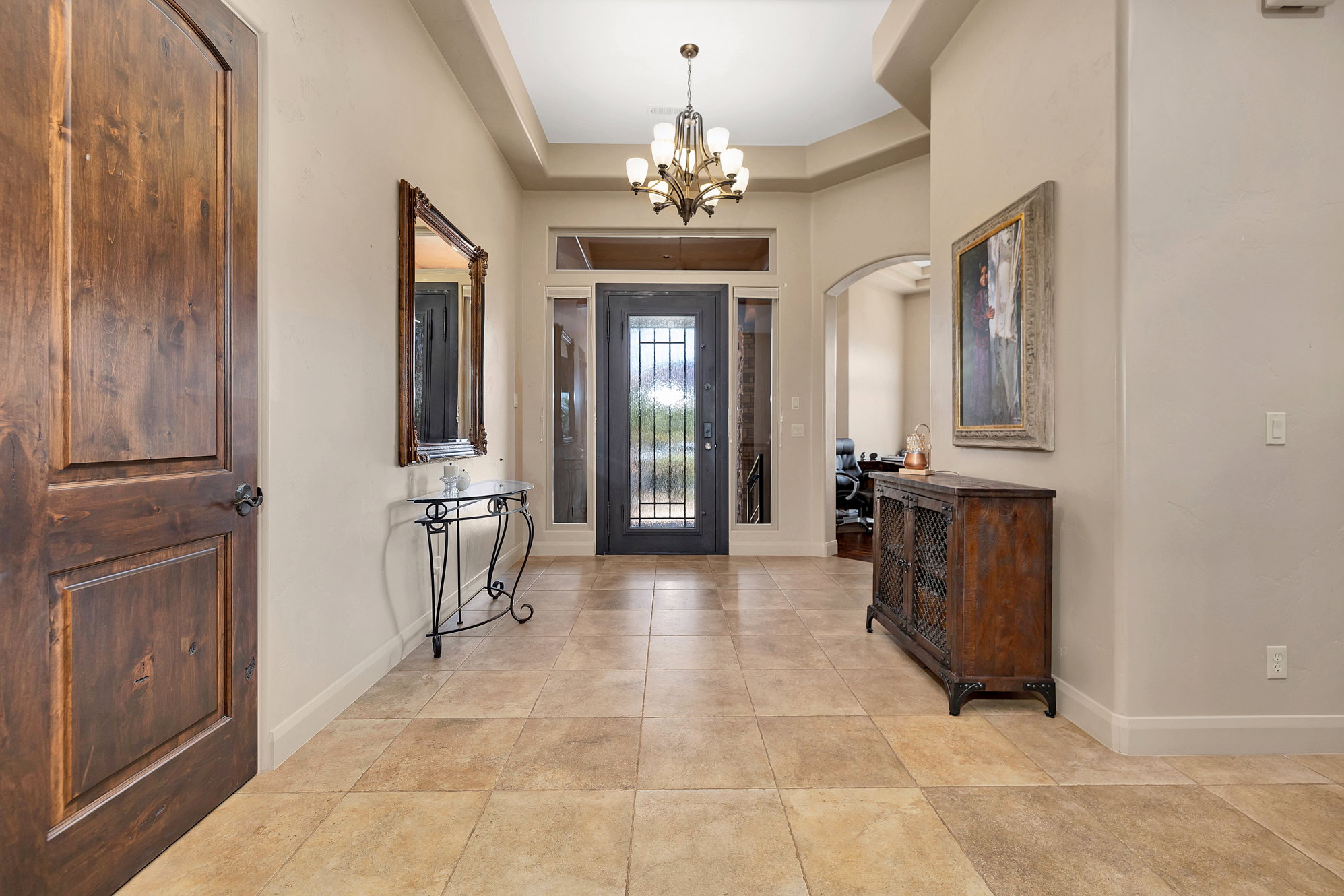 Entrance foyer featuring hanging lights, a tray ceiling, and arched walkways