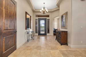 Entrance foyer featuring hanging lights, a tray ceiling, and arched walkways