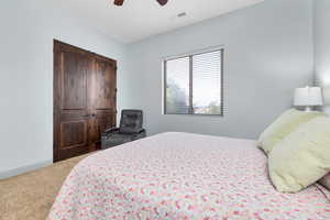 Bedroom with light carpet, a closet, and a ceiling fan