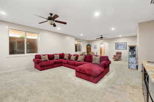 Living area with ceiling fan, arched walkways, light colored carpet, and recessed lighting