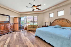 Bedroom featuring light wood-type flooring, a sauna / steam room, access to outside, a tray ceiling, and multiple windows