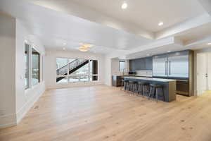Kitchen featuring a kitchen bar, light wood-type flooring, stainless steel appliances, a kitchen island, and recessed lighting