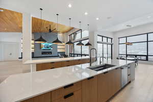 Kitchen with modern cabinets, light wood-style flooring, light stone countertops, and wood ceiling