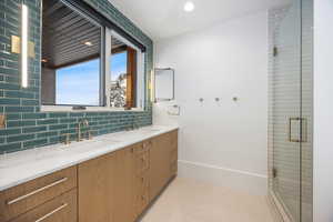 Full bath featuring double vanity, a stall shower, tasteful backsplash, and recessed lighting