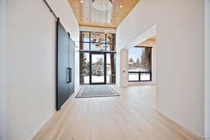 Foyer featuring a high wood ceiling, a barn door, light wood-style floors, and recessed lighting