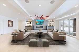 Living room featuring light wood-style floors, a ceiling fan, recessed lighting, and a glass covered fireplace