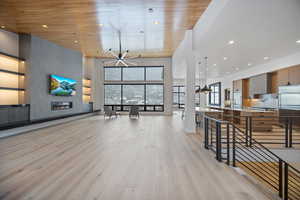 Living area featuring light wood-style flooring, a large fireplace, recessed lighting, and a high wood ceiling